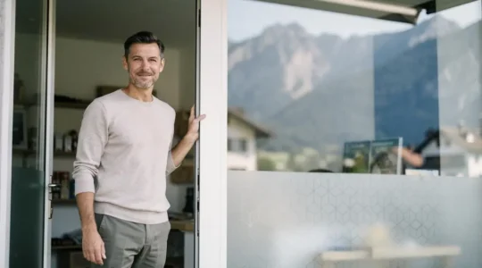Entrepreneur indépendant suisse debout devant son atelier, symbolisant la sécurité apportée par une couverture d'assurance solide