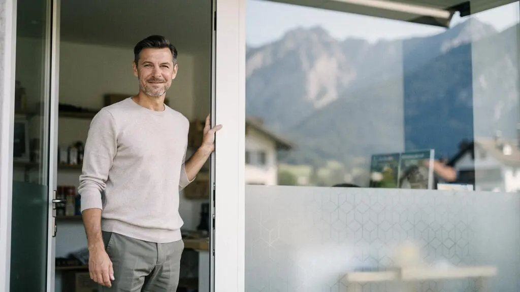 Entrepreneur indépendant suisse debout devant son atelier, symbolisant la sécurité apportée par une couverture d'assurance solide