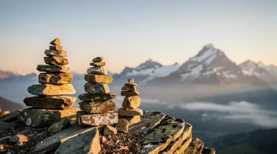 Photographie editoriale de trois piliers de pierre suisses face a un paysage alpin, symbolisant le systeme des 3 piliers de la retraite
