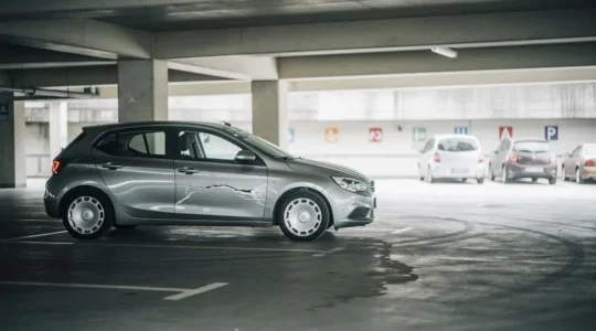 Voiture garée avec une rayure sur la portière dans un parking suisse, aucun responsable en vue